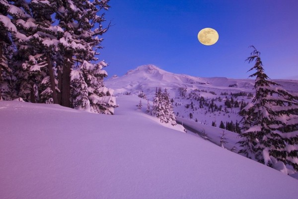 Luna llena sobre montañas nevadas