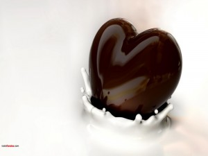 Corazón de chocolate negro sumergiéndose en leche