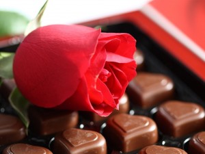 Una rosa roja con bombones de chocolate