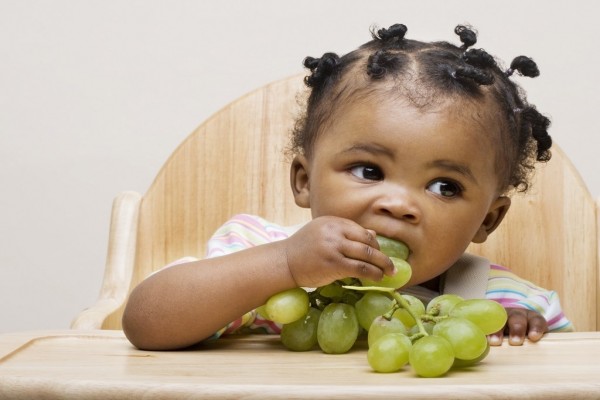 Niña pequeña comiendo uvas blancas