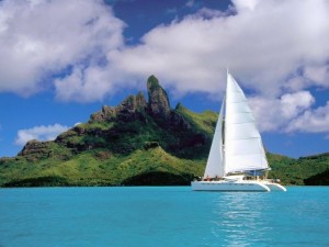 Postal: Catamarán a vela surcando aguas azules