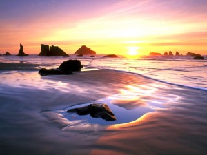 Postal: Amanecer en una playa de arena y rocas