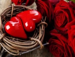 Dos corazones en una cesta, junto a unas rosas rojas