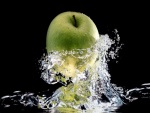 Manzana verde cayendo al agua