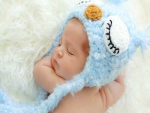 Bebé durmiendo con un gorro azul