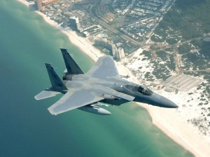 Postal: Avión de combate sobrevolando una playa