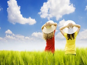 Postal: Dos niñas con sombrero en un campo de verdes espigas