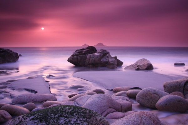Atardecer rosado en una playa rocosa