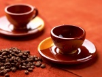 Dos tazas rojas y granos de café