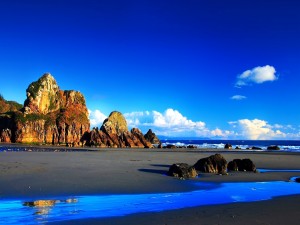 Playa con grandes rocas y un cielo azul