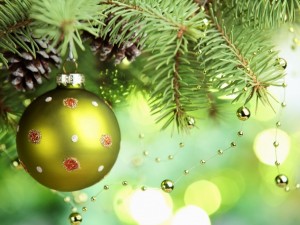 Bola verde colgada de la rama de un arbolito de Navidad