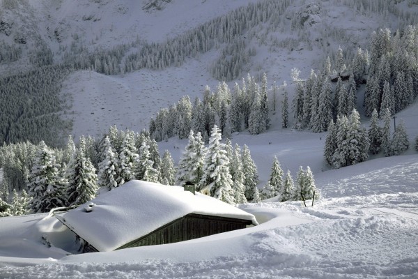 Cabaña cubierta de nieve cerca de la pista de esquí