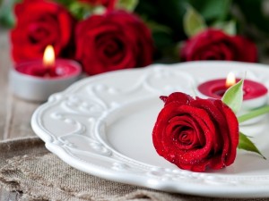 Rosa roja sobre un plato y velas