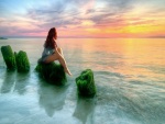 Sentada frente al mar observando la puesta del sol