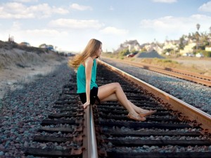 Chica sentada en la vía del tren