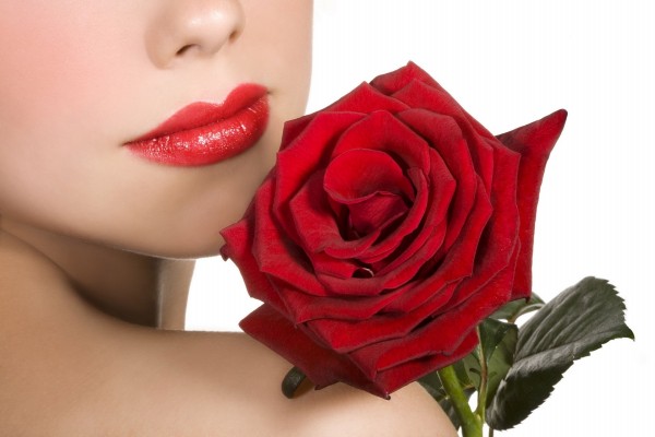 Unos rojos labios de mujer, junto a una rosa roja