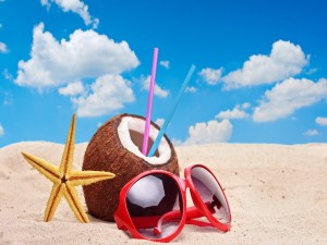 Gafas de sol, coco y estrella sobre la arena