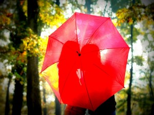 Pareja de enamorados, detrás de un paraguas rojo