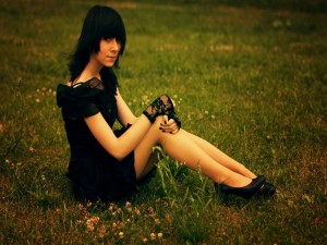 Chica vestida de negro, sentada en la hierba