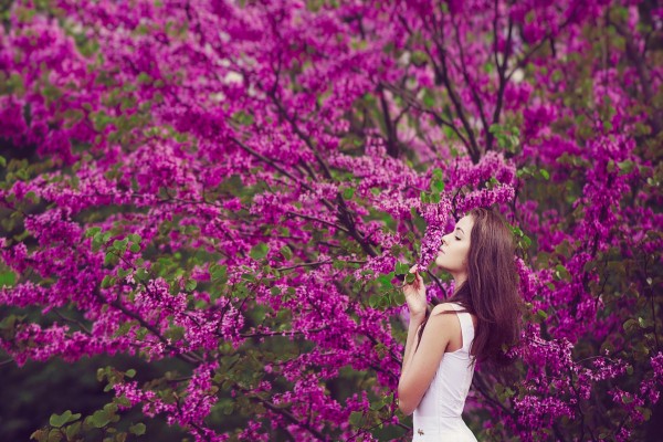 Mujer aspirando el aroma de las flores color púrpura