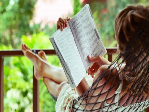 Postal: Una chica leyendo un libro en una hamaca