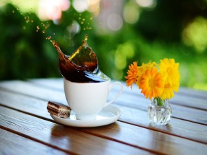 Café en movimiento y un pequeño jarrón con flores