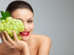 Bella mujer con un racimo de uvas verdes