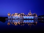 Un castillo reflejado en el agua durante la noche