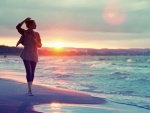 Mujer paseando por la playa a la salida del sol