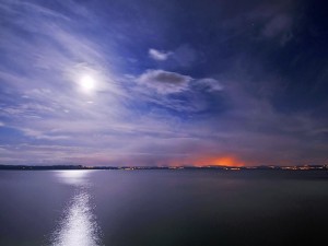 La luna entre las nubes iluminando el agua