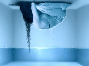 Mujer encogida al otro lado del agua