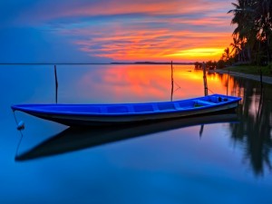 Postal: Un bote en el agua a la entrada del sol