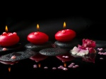 Guijarros, perlas y velas encendidas de color rojo