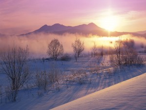 El sol al amanecer sobre un paisaje cubierto de nieve