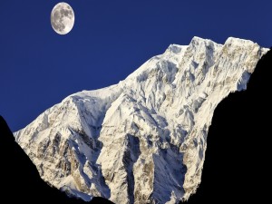 Resplandeciente Luna iluminando los picos montañosos cubiertos de nieve