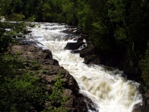 Postal: Un caudaloso río entre rocas y árboles