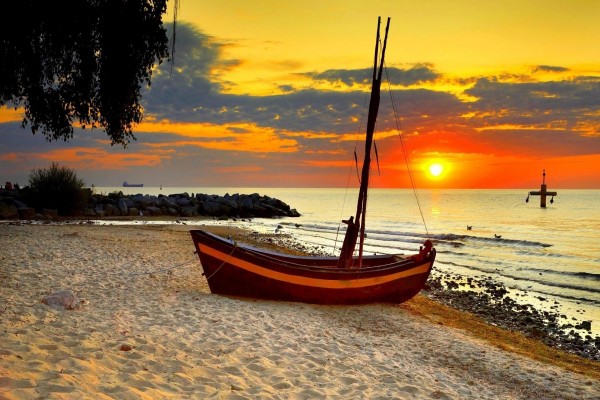 Barca sobre la arena de la playa en el ocaso del sol
