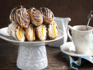 Exquisitos cannoli con nata y chocolate acompañados de una taza de café