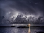 Faro iluminando en una noche de tormenta eléctrica