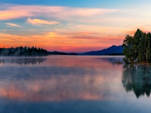 Cielo al amanecer y árboles reflejados en las tranquilas aguas del lago