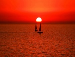 El sol se esconde, iluminando los barcos a vela