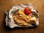 Tallarines frescos, queso y un tomate sobre el mismo papel