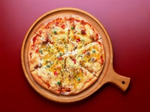 Postal: Pizza en una tabla de madera redonda