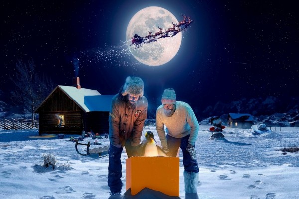 Hombres y un pingüino admirando una caja la noche de Navidad