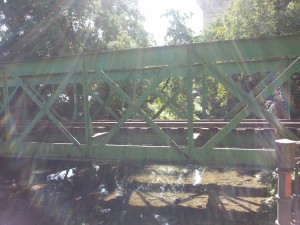 Postal: Rayos de sol iluminando un puente de hierro
