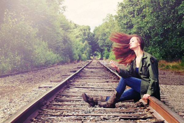 Una joven sentada en la vía del tren
