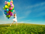 Una joven en un prado con muchos globos de colores