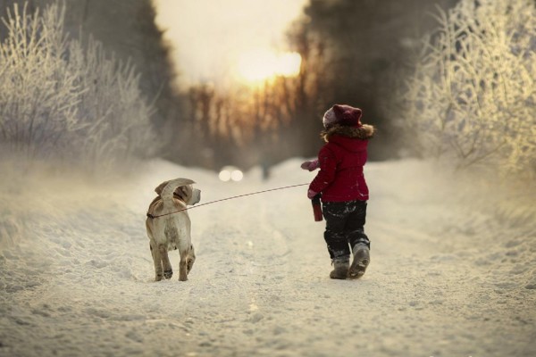 Niña paseando a su perro por la nieve