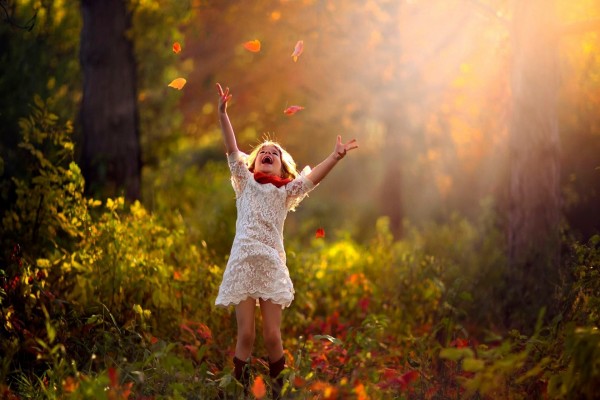 Una niña muy alegre saltando en un bosque otoñal