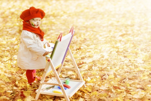 Una bella niña pintando en un espléndido día de otoño